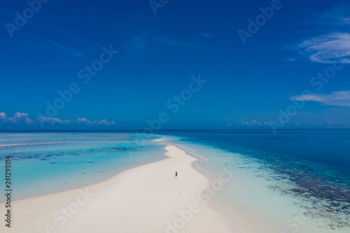 Fototapeta Naklejka Na Ścianę i Meble -  Aerial view of a man walking on the white sand bar in the tropical destination. Hawaii French polynesia Maledives Philippines.