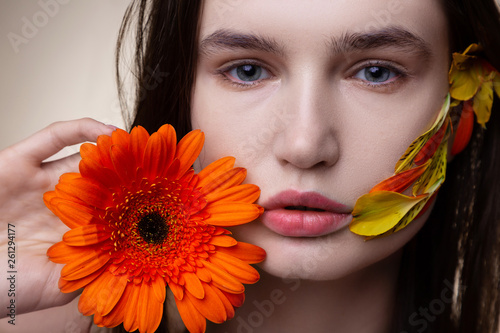 Close up of model with natural look holding nice orange flower