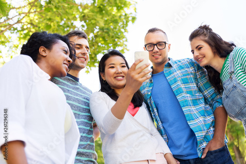 friendship, technology and international concept - group of friends with smartphone at summer park