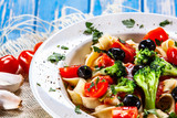 Pasta with herbs and vegetables on wooden background