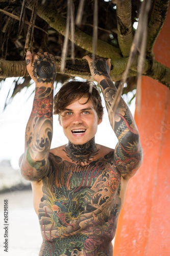 Photography Attractive male surfer in tattoos on the ocean with an orange bright longboard surfboard