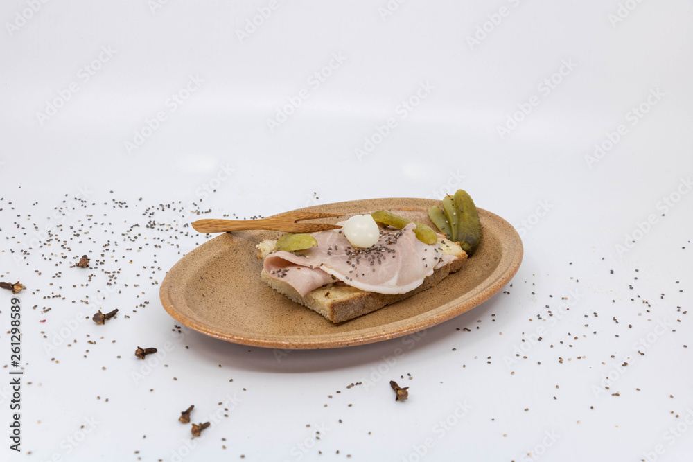 Sandwich jambon beurre cornichon servi dans une assiette en céramique