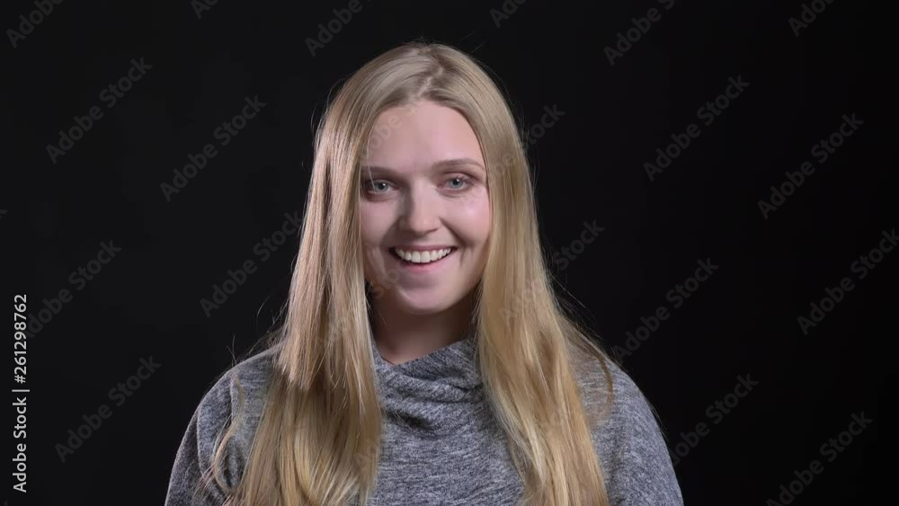 Portrait of young blonde straight-haired model showing joyful amusement into camera on black background. Portrait of young blonde straight-haired model showing joyful amusement into camera on black background.