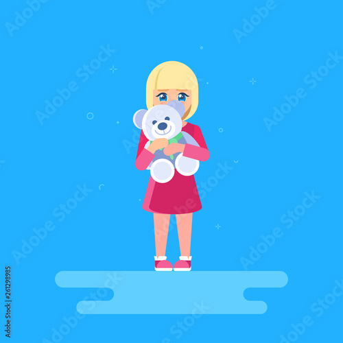 The girl is hugging a teddy bear. She is standing at full length and hiding behind a toy. The shy child.