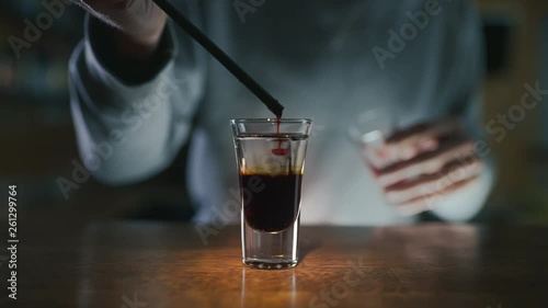 Barman adds sirop to the layered shot with dakr liquor and gin in slow motion, making cocktails in a bar, alcohol drink, bar party, 4k UHD 60p video in Prores HQ 422 photo