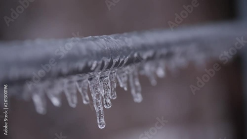 Frozen stalactites hanging from a metal rail with focus pull.