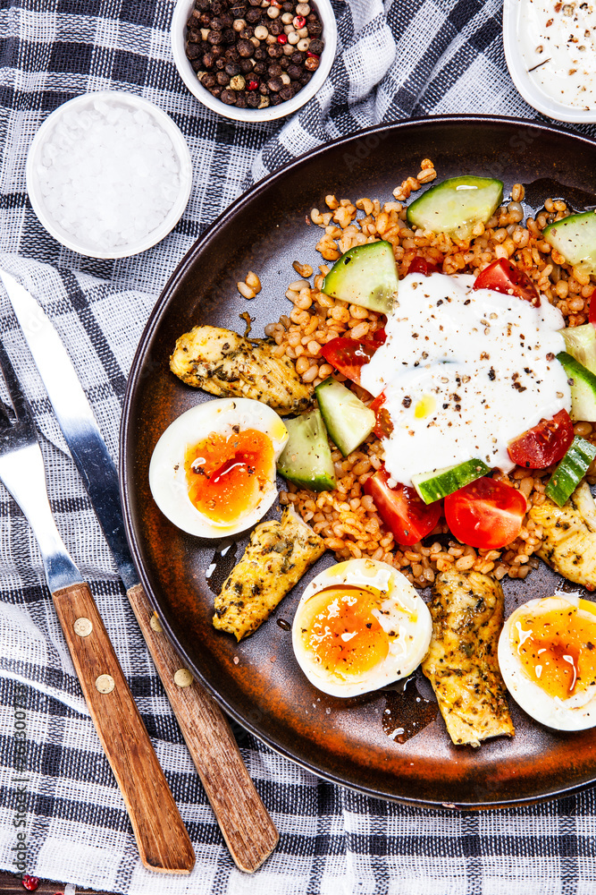 Grilled chicken meat with groats and boiled egg on wooden table Grilled chicken meat with groats and boiled egg on wooden table