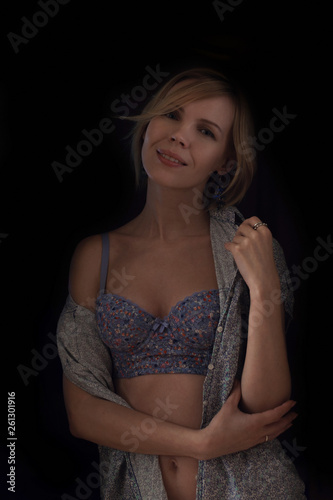 Middle-aged woman in bra on a dark background.