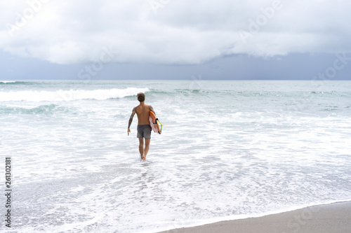 Photography Attractive male surfer in tattoos on the ocean with an orange bright longboard surfboard