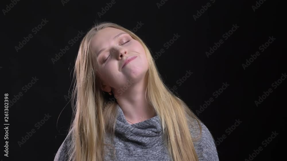 Portrait of young blonde straight-haired model standing with closed eyes in satisfaction on black background. Portrait of young blonde straight-haired model standing with closed eyes in satisfaction on black background.