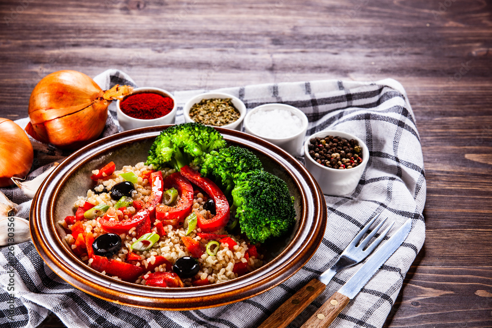 Groats with vegetables on wooden table