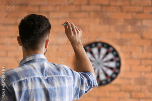 Young man playing darts indoors photo