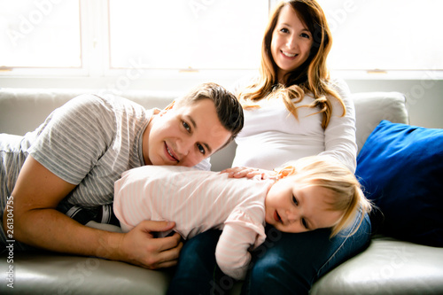 A Beautiful pregnant mother and father with her children girl at the living room