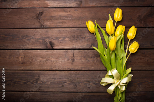 Spring card: yellow tulips on a dark wooden background. Top view, lay flat