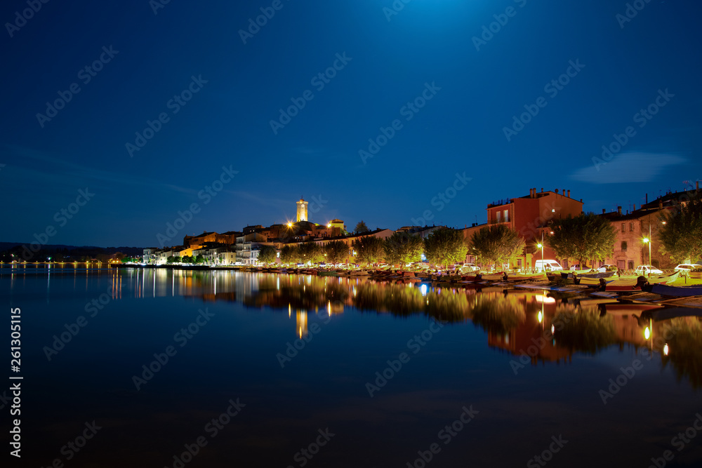 Panorama notturno di Marta VT, Italia che si riflette sulle acque del Lago di Bolsena.