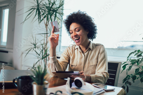 African american woman with digital tablet and credit card in home office