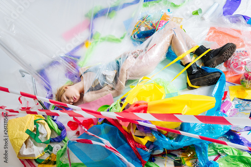 Model closing eyes while posing on floor wrapped into plastic