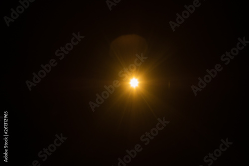 Single spark on black background. Lens flare effect. Defocused rays and lights.