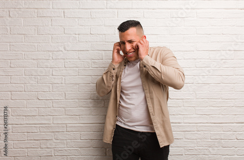 Young latin man covering ears with hands