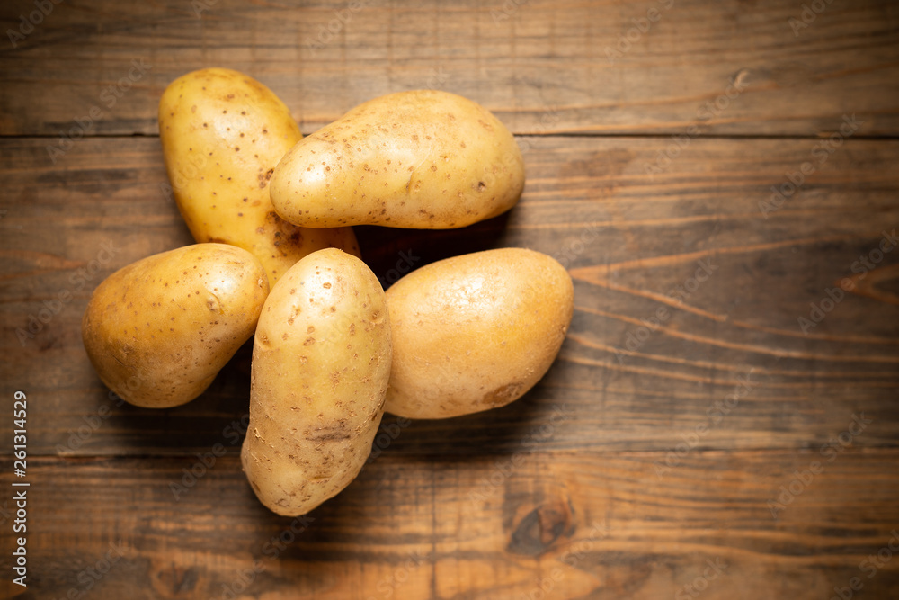 Raw potato on wooden background.