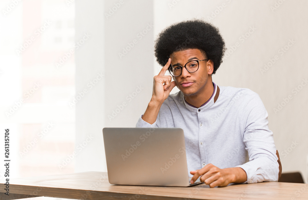 Young black man using his laptop thinking about an idea Young black man using his laptop thinking about an idea