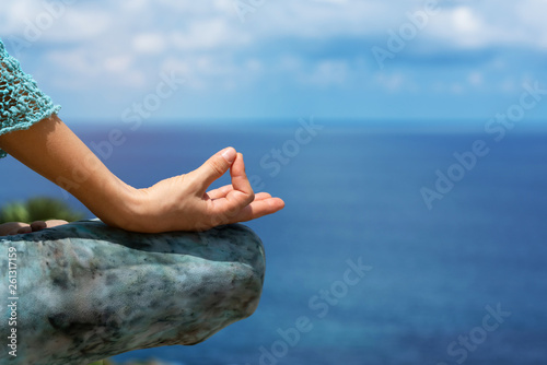 Woman sitting in yoga on mountain near the Andaman Sea. On holiday season of the summer Relaxing muscles meditating with nature. Bright sunshine The body is getting healthy vitamin. close up for hand