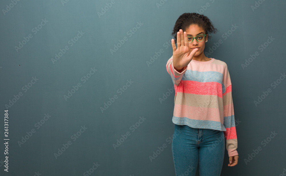 Young african american girl with blue eyes putting hand in front