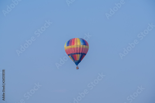 Hot air balloon over cosmos flowers with blue sky © tomruethai