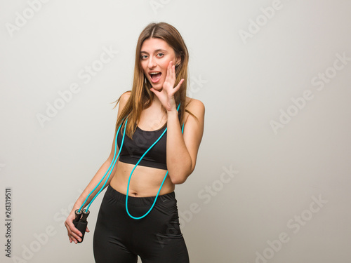 Young fitness russian woman shouting something happy to the front. Holding a jump rope. © Asier