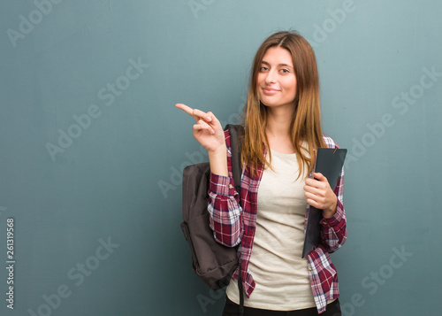 Young student russian woman smiling and pointing to the side