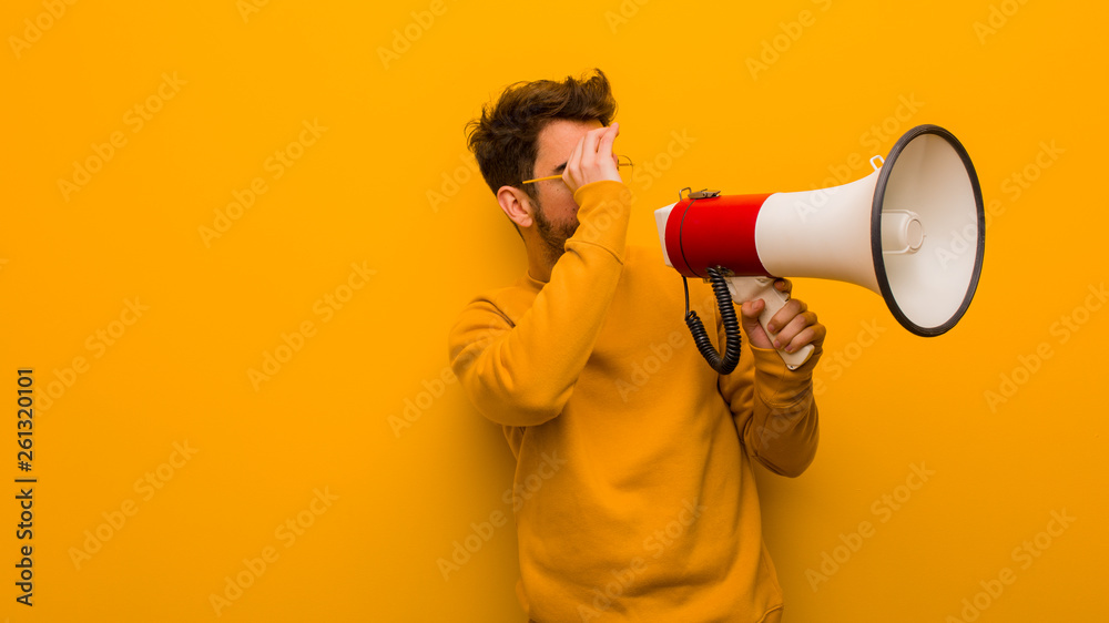 Young man holding a megaphone making the gesture of a spyglass Young man holding a megaphone making the gesture of a spyglass