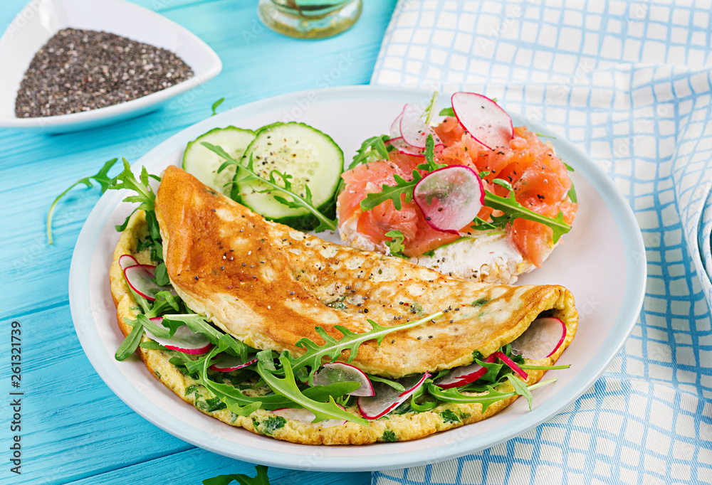Breakfast. Omelette with radish, green arugula and sandwich with salmon on white plate.  Frittata - italian omelet.
