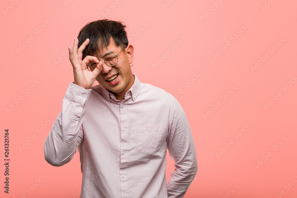 Young chinese man confident doing ok gesture on eye Young chinese man confident doing ok gesture on eye