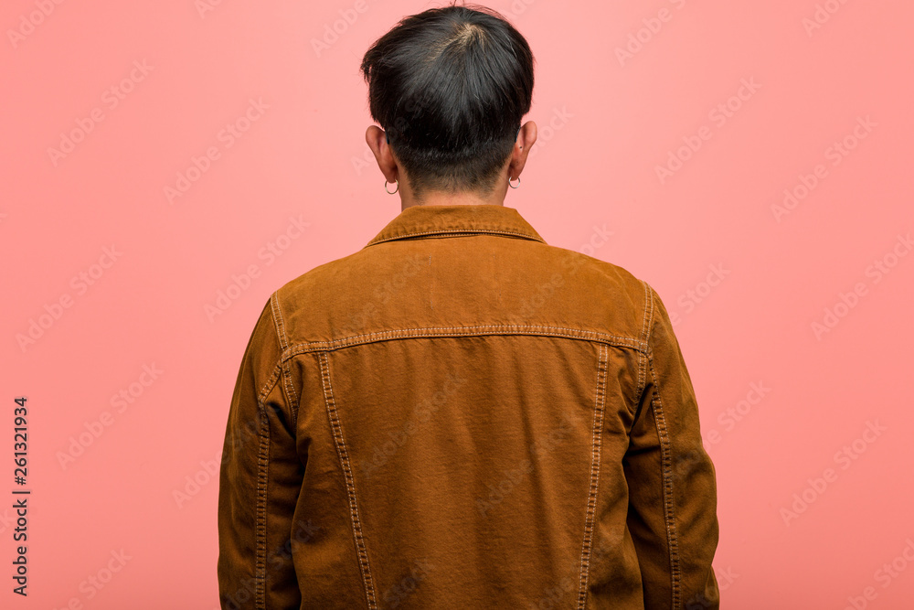 Young chinese man wearing a jacket from behind, looking back Young chinese man wearing a jacket from behind, looking back