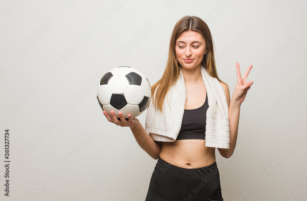 Young fitness russian woman fun and happy doing a gesture of victory. Holding a soccer ball.