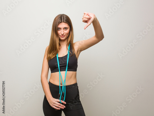 Young fitness russian woman pointing fingers, example to follow. Holding a jump rope. © Asier