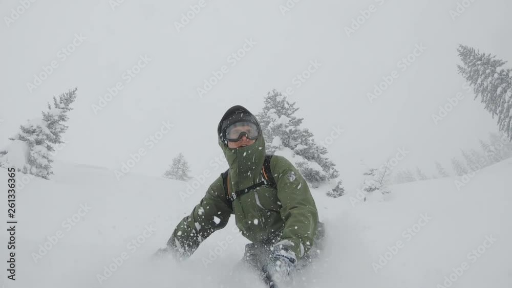 ACTION: A snowboarder rides through deep powder while the snow splashes in his face. Winter sports in frozen wonderland.