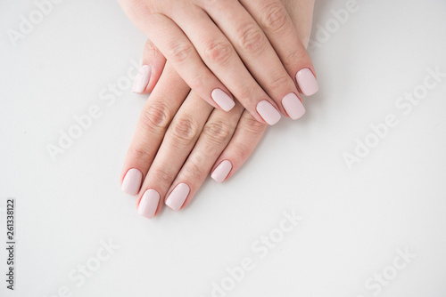 Manicured hands on white background. Hands with manicured nails colored with beige nail polish.