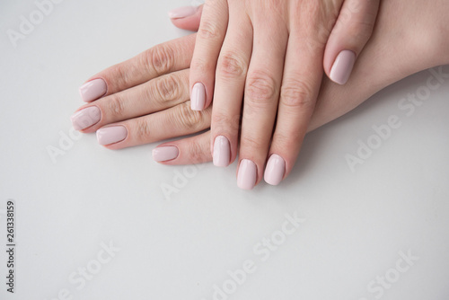 Manicured hands on white background. Hands with manicured nails colored with beige nail polish.