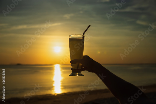 Orange juice in woman hands on the beach with sea background
