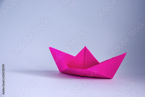 Pink origami paper boat on wooden background. Origami ship 