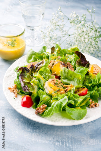 Traditioneller deutscher Sommer Salat mit Blattsalat   Ziegenk  se und Mango Dressing als closeup auf einem Teller auf einem gedeckten Tisch