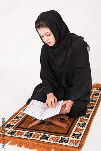 Arab muslim woman reading the holy Quran and praying photo