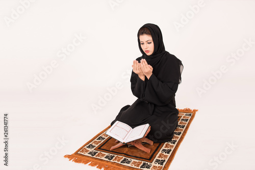 Arab muslim woman reading the holy Quran and praying photo