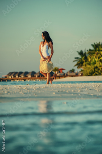 beautiful young woman posing on white beach, beautiful scenery with woman in maldives, tropical paradise photo