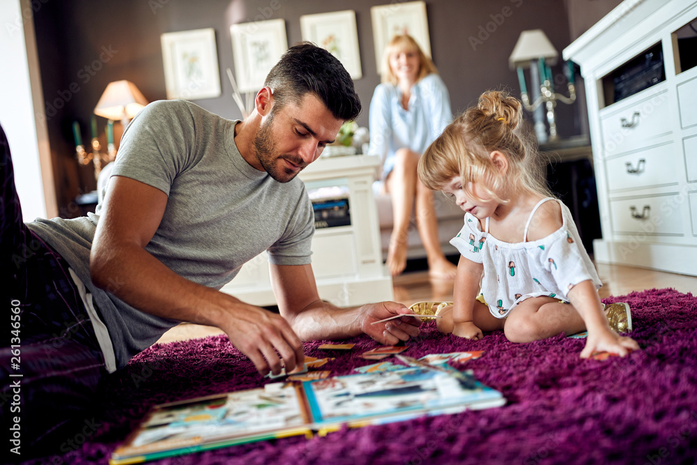 Fototapeta premium Dad with daughter playing with puzzles