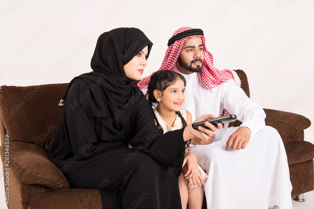 Arab family watching TV at home and using remote control