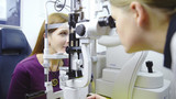 Female optometrist looking inside the device of patient eyeballs