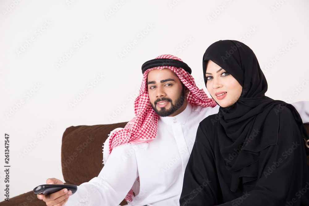 Arab family watching TV at home and using remote control