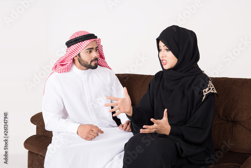 Arab couple fighting and discussing family issues while sitting on sofa chair at home photo